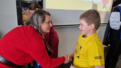 Radní paní Hana Balcarová předává  pasovanému malému čtenáři taštičku s drobnými dárky